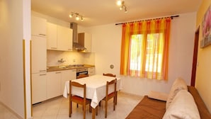 A compact kitchen with white cabinets, a dining table with chairs, and a sofa. - Ground floor retreat with bbq (Rovinj)
