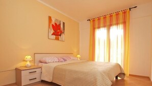 A bedroom with a bed, nightstands, a lamp, and a painting on the wall. - Ground floor retreat with bbq (Rovinj)