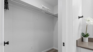 A minimalist room with a wooden floor, white walls, a towel rack, a potted plant, and a door with a black handle. - Touch of Class - 5BR - Private Hot Tub & Near Zion (Hurricane)