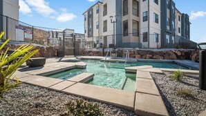 A modern apartment building with a swimming pool and outdoor seating area.