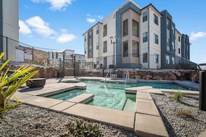 A modern apartment building with a swimming pool and outdoor seating area.