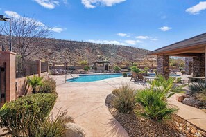 A backyard with a swimming pool, patio furniture, and a stone building.