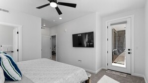 A bedroom with a bed, a ceiling fan, a TV, and a door leading to a balcony. - Touch of Class - 5BR - Private Hot Tub & Near Zion (Hurricane)