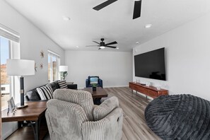 A modern living room with a sofa, a coffee table, a TV, and a ceiling fan.