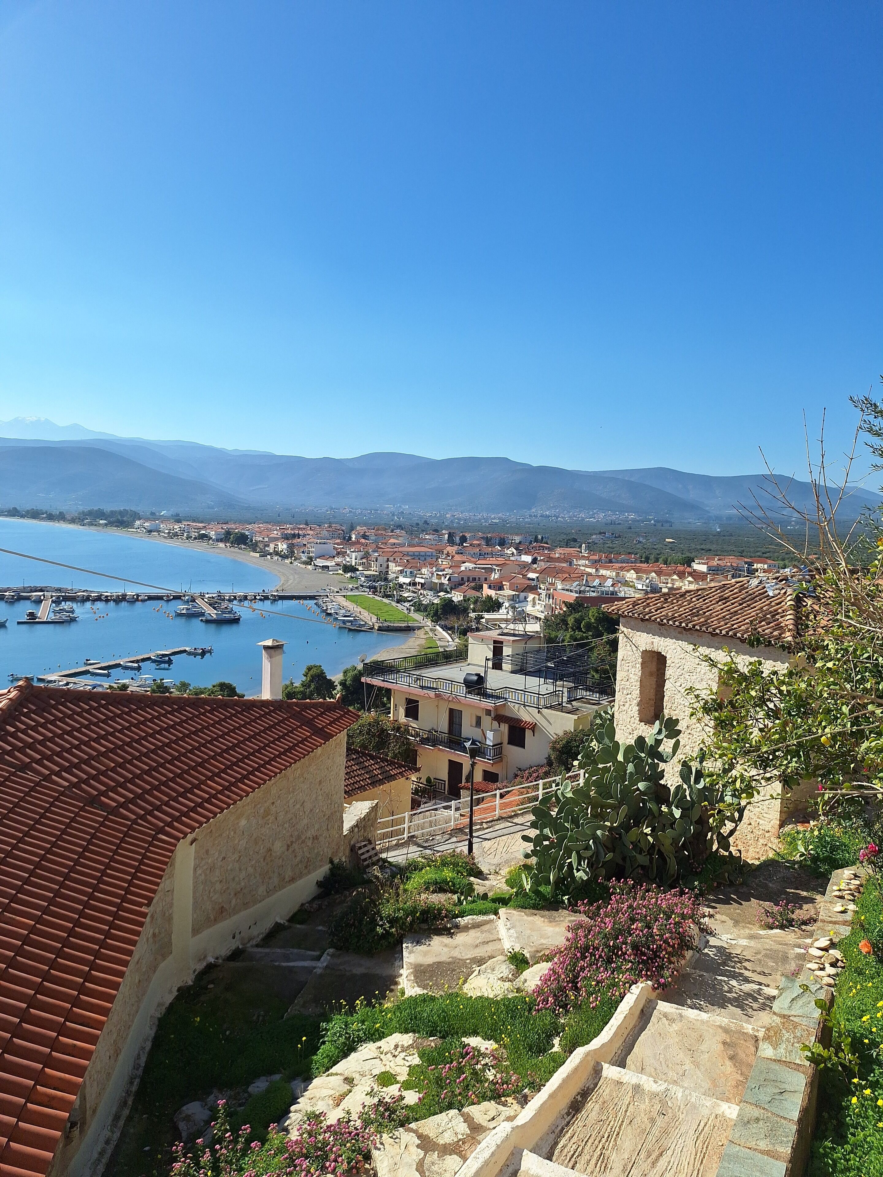 A coastal town with a marina, terraced houses, and a mountainous backdrop.