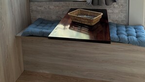 A compact room with a window, a small table with a basket, and a cushioned bench. - GARDEN APARTMENT (ELECTRIC CAR CHARGING STATION) (North Kynouria)