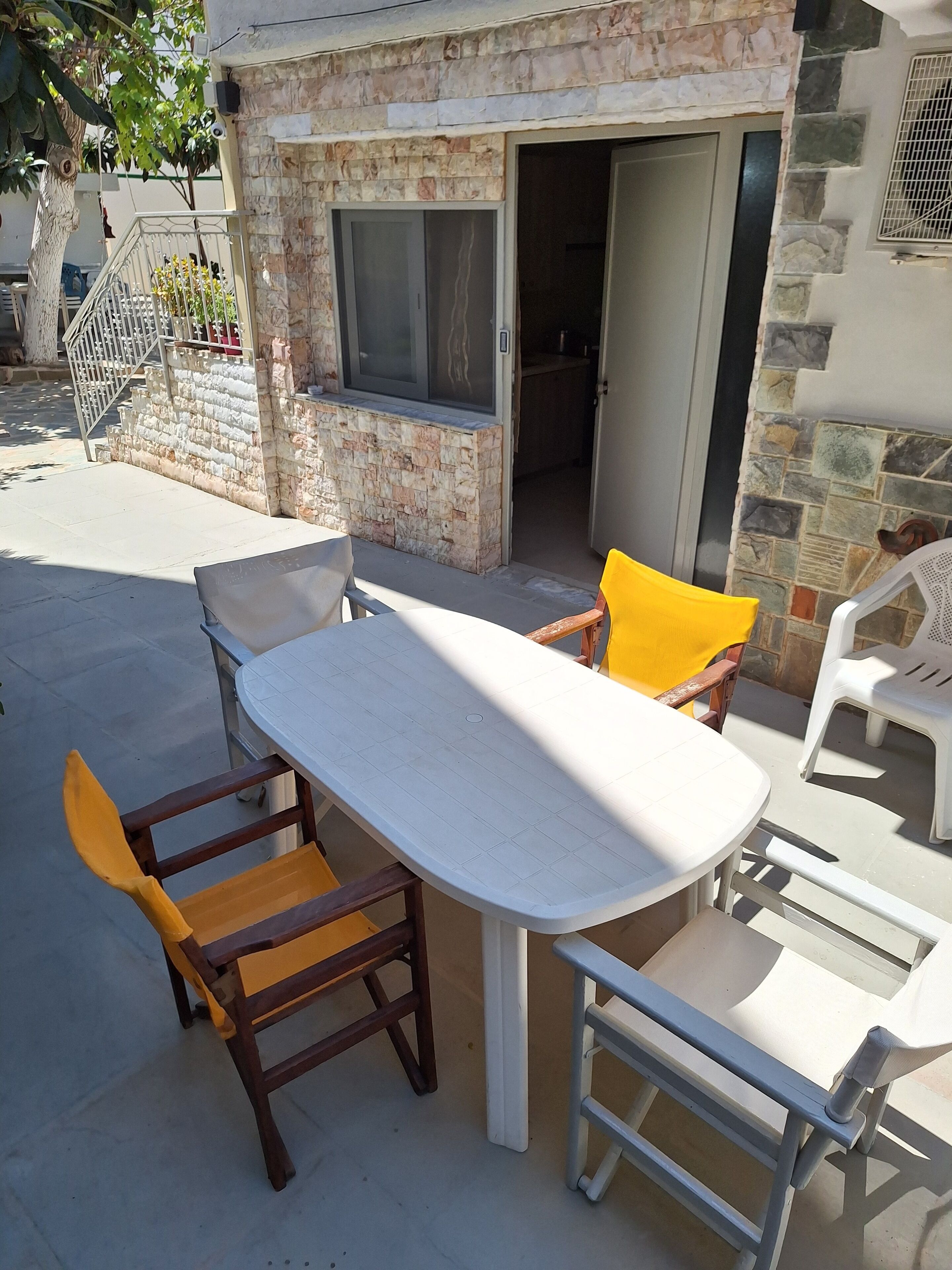 An outdoor patio with a table and chairs, a stone wall, and a door leading to an interior space.