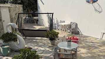 A courtyard with outdoor seating, potted plants, and a swan sculpture.
