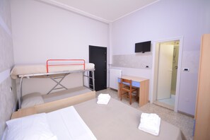 Une petite pièce comprenant des lits superposés, un bureau, une chaise, un radiateur et un téléviseur.