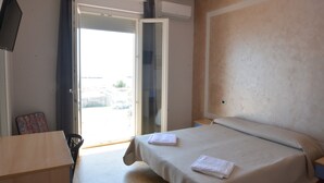 A hotel room with a bed, a desk, a chair, a TV, and a sliding door to the outside. - HOTEL  BELLA ROMAGNA     (Ravenna)