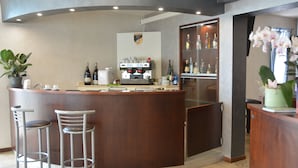 A bar area with a counter, stools, a coffee machine, and a wine bottle. - HOTEL  BELLA ROMAGNA     (Ravenna)