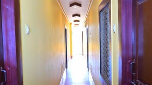 Ein Hotelkorridor mit Fliesenboden, Holztüren und einer Decke mit eingelassener Beleuchtung.