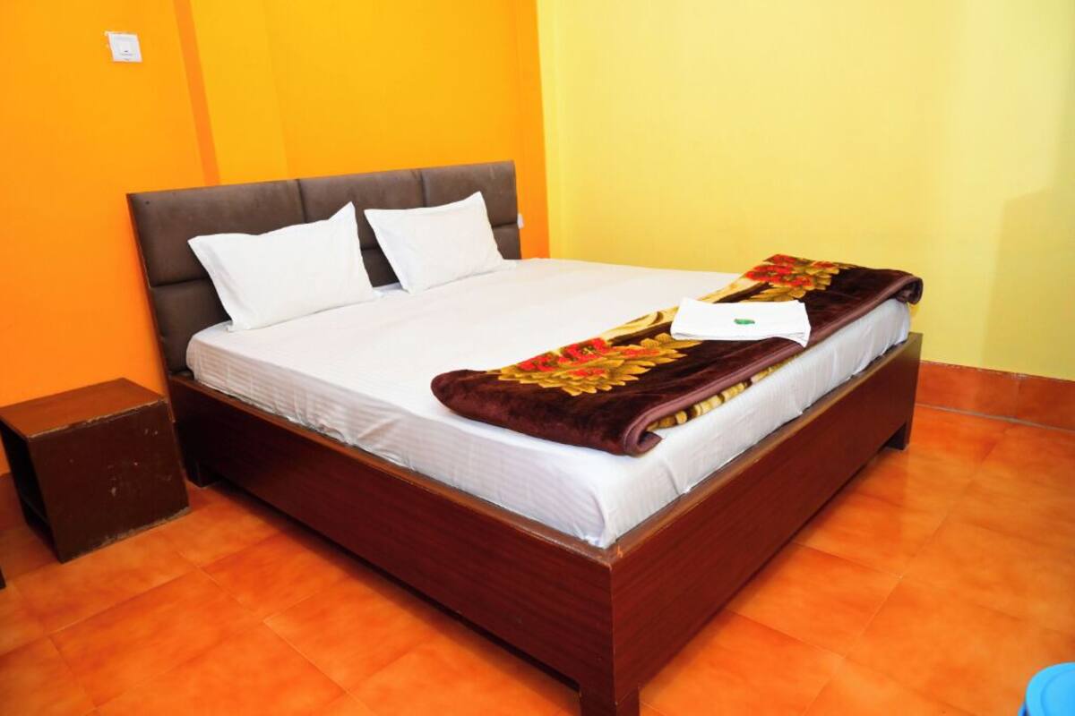 Una cama individual con cabecera marrón, ropa de cama blanca y una manta decorativa.