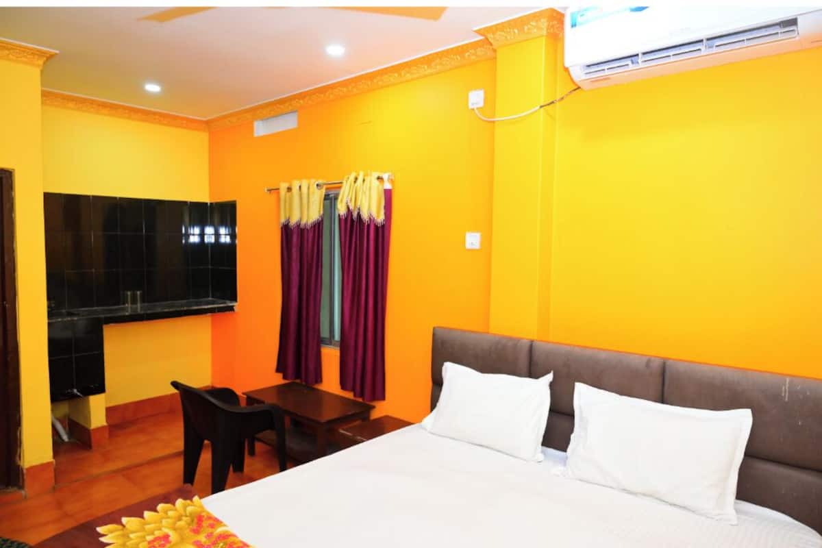 Una habitación de hotel con cama, escritorio, silla y ventana con cortinas.