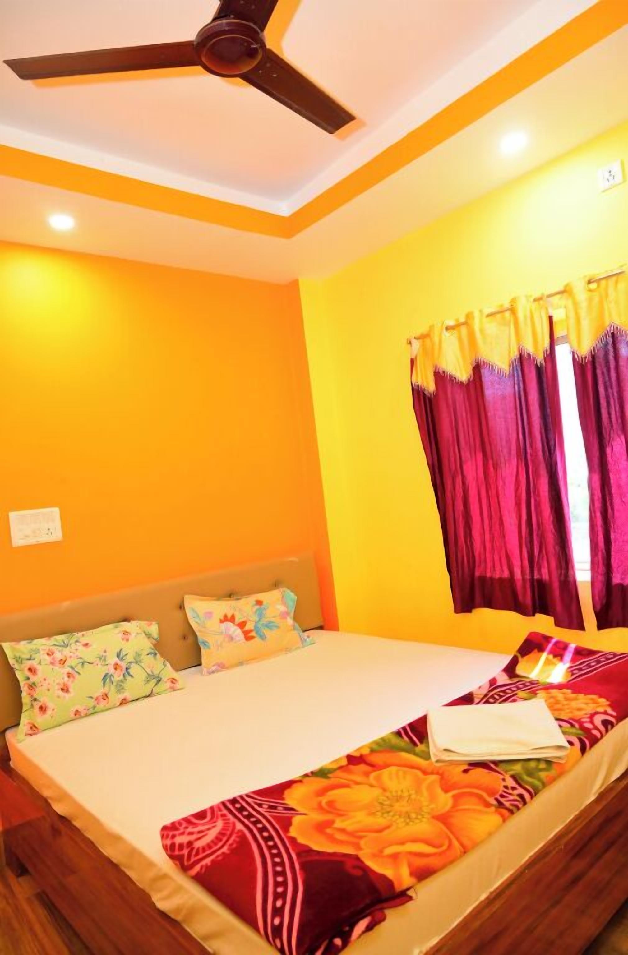 A bedroom with a bed, a ceiling fan, and curtains.