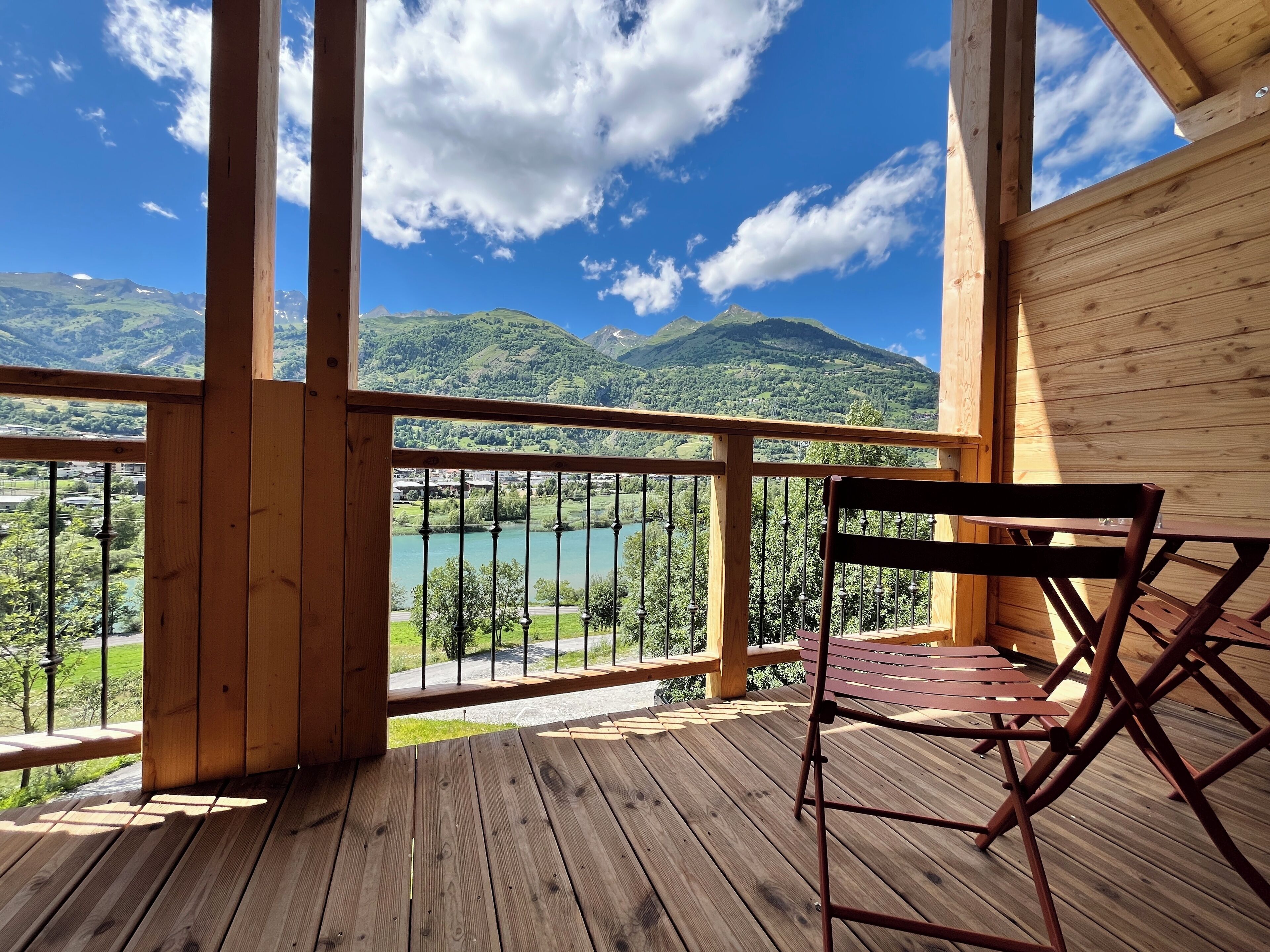 Un terrazzo in legno con vista su un lago e montagne.