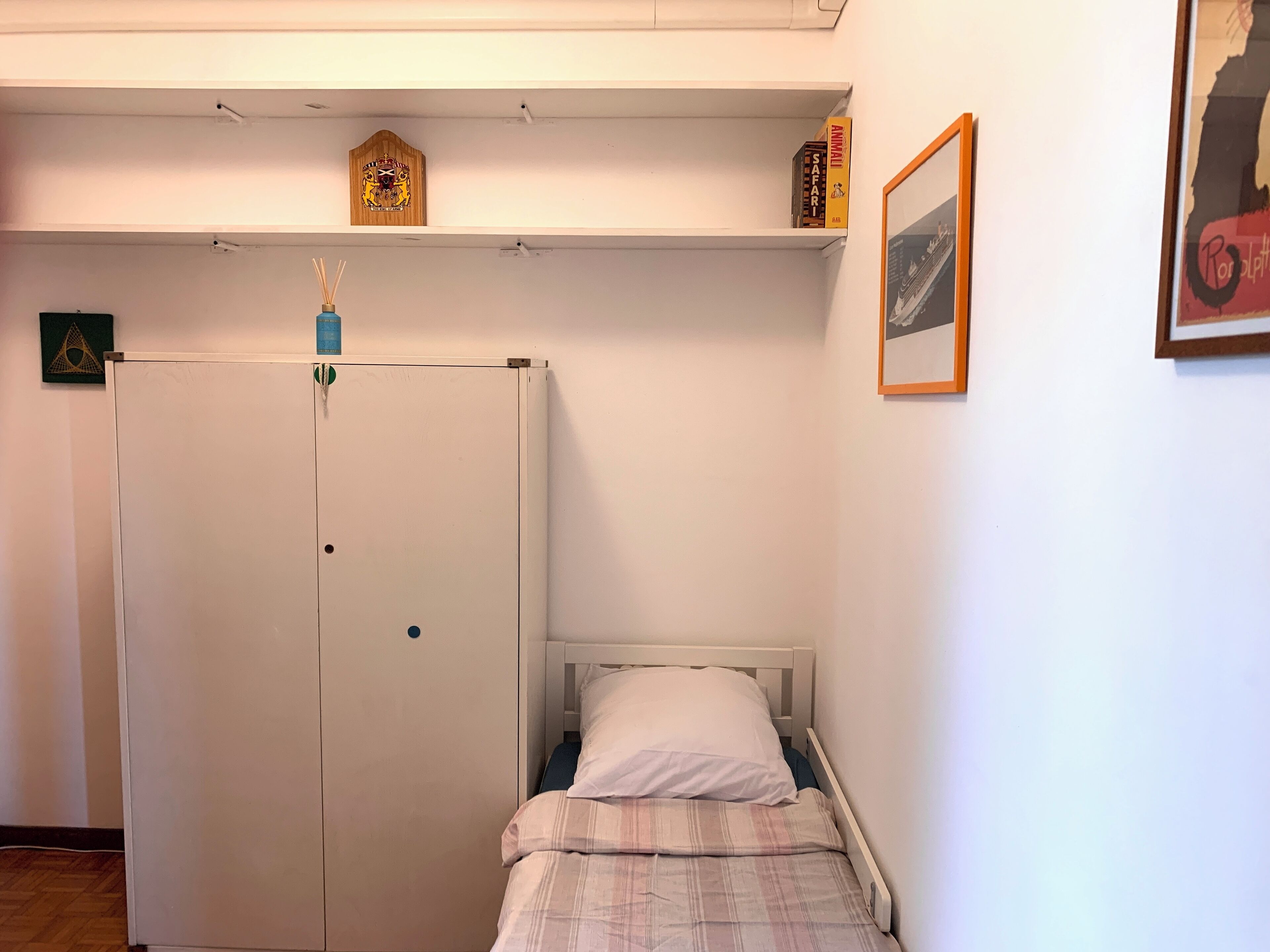 Une chambre à coucher avec un lit, une armoire et une petite étagère remplie de livres.