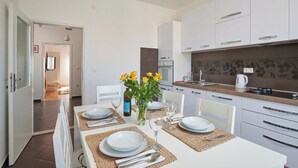 Una cucina moderna con mobili bianchi, un tavolo da pranzo apparecchiato con piatti, bicchieri e un vaso di fiori gialli.