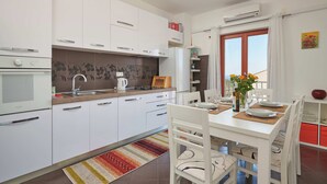 Una cucina moderna con mobili bianchi, forno integrato e zona pranzo con tavolo apparecchiato per due.
