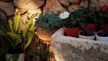 Un muro de piedra con plantas en macetas y un objeto metálico colgante.