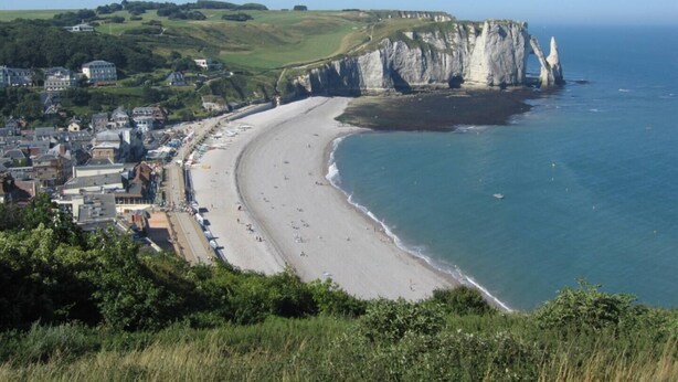 A coastal town with a long sandy beach, cliffs, and a view of the sea.