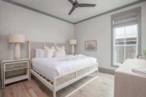 A bedroom with a bed, nightstands, a desk, a ceiling fan, and a window with blinds. - Newly Built Lux Grayton Beach Home "Timeless 30A" Pool, Golf Cart, Bikes (Santa Rosa Beach)