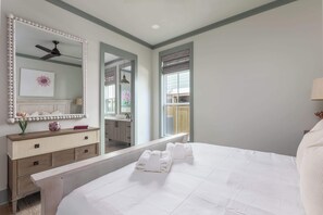 A bedroom with a large bed, a dresser, a mirror, and a window.