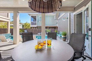 Eine Terrasse im Freien mit einem Tisch für zwei Personen, ausgestattet mit einem Eisteekrug und Zitronen, umgeben von Korbstühlen.