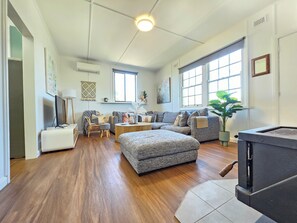 Relax in this spacious living room with a high ceiling, large windows, and a cozy fireplace.