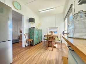 Enjoy meals in this kitchen with a dining table and chairs, a vintage-style cabinet, and a large glass vase.