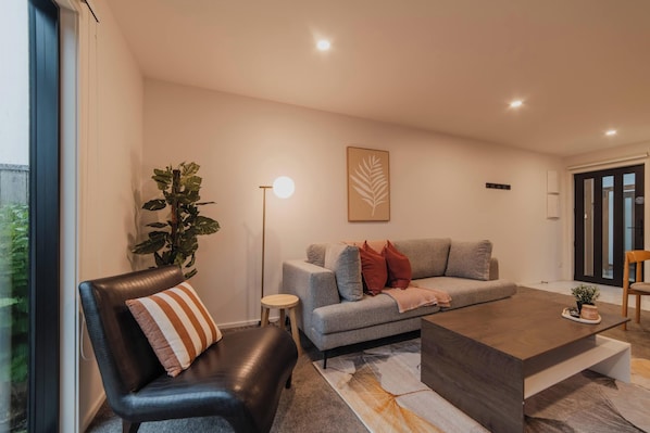 A modern living room with a grey sofa, a black leather chair, a coffee table, and a floor lamp.