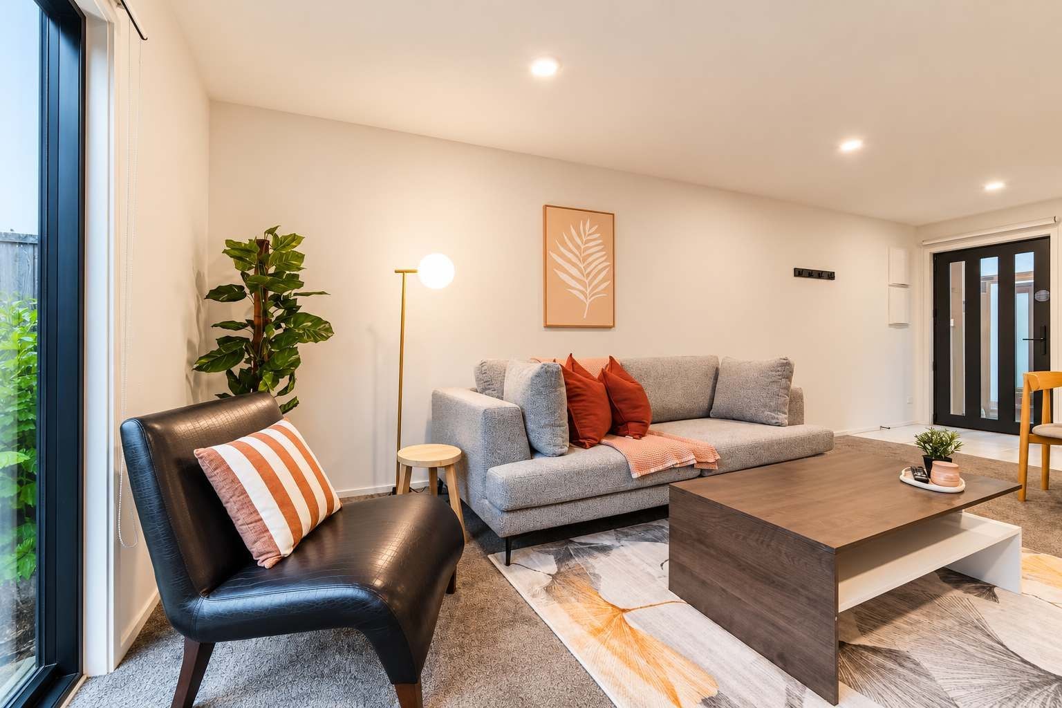 A modern living room with a leather chair, grey sofa, and a coffee table.