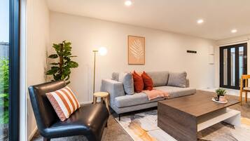 A modern living room with a leather chair, grey sofa, and a coffee table.