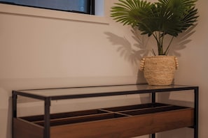 Et moderne konsolbord med en vævet kurv med en plante, placeret op ad en væg med et vindue over.