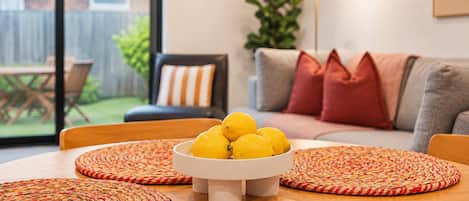 Un comedor con una mesa redonda, un cuenco de limones y caminos de mimbre.