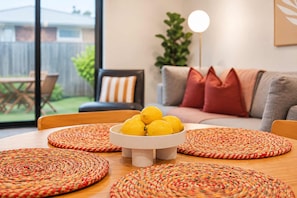 A dining area with a round table, a bowl of lemons, and woven placemats.