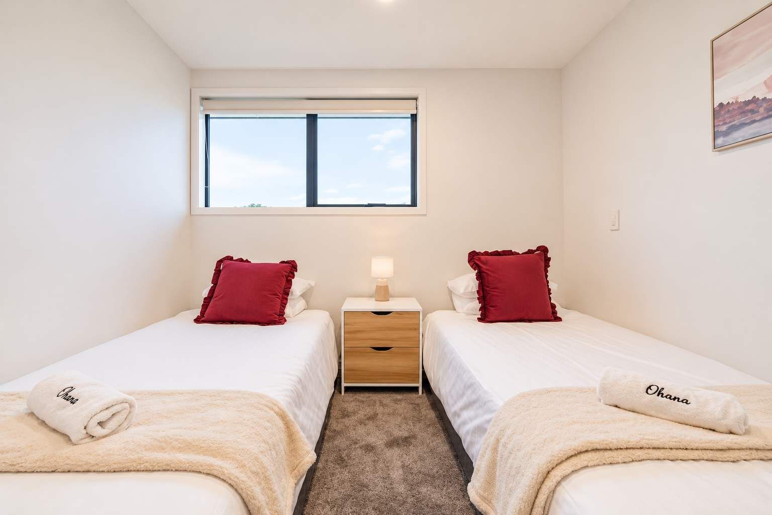 A twin room with two beds, a nightstand, a window, and a painting on the wall.