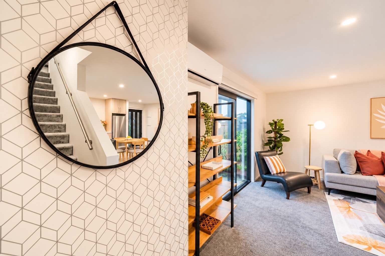 Un intérieur moderne comprenant un escalier, un coin repas et un salon avec un canapé et une table basse.