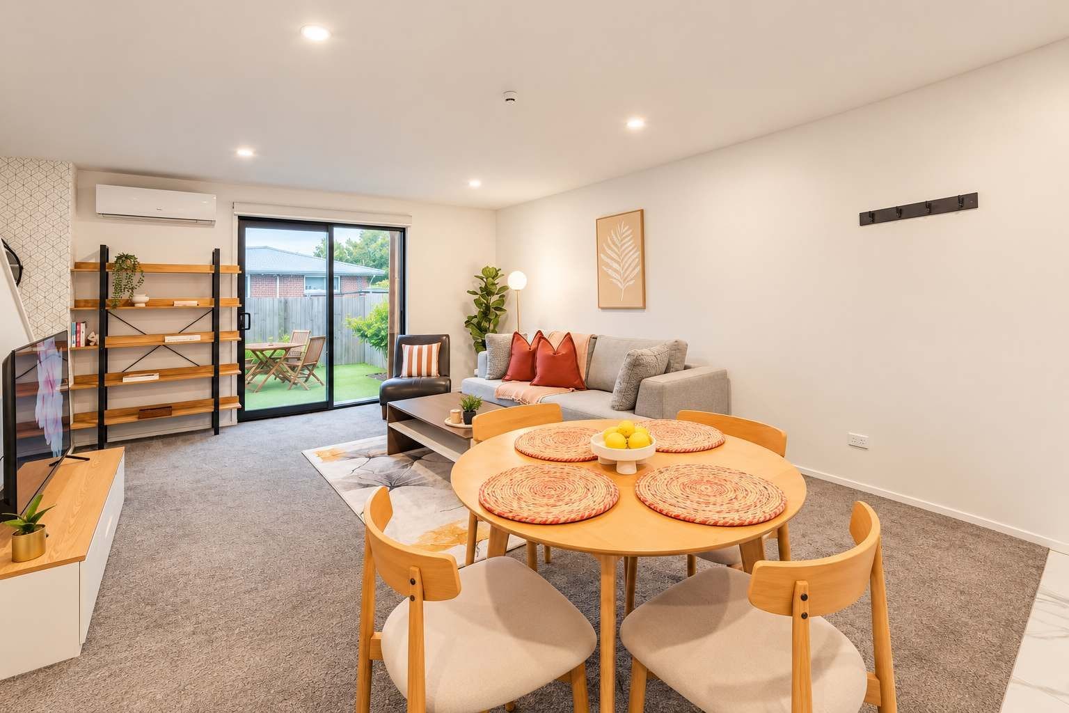 A modern living room with a dining area, a sofa, a coffee table, and a TV.