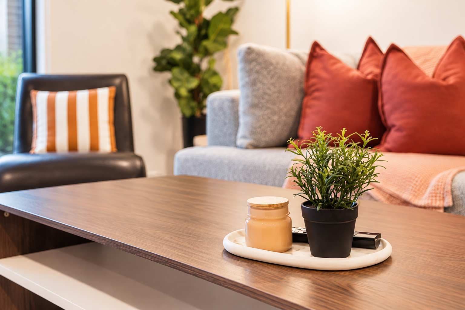 A wooden table with a potted plant and a candle on a tray.