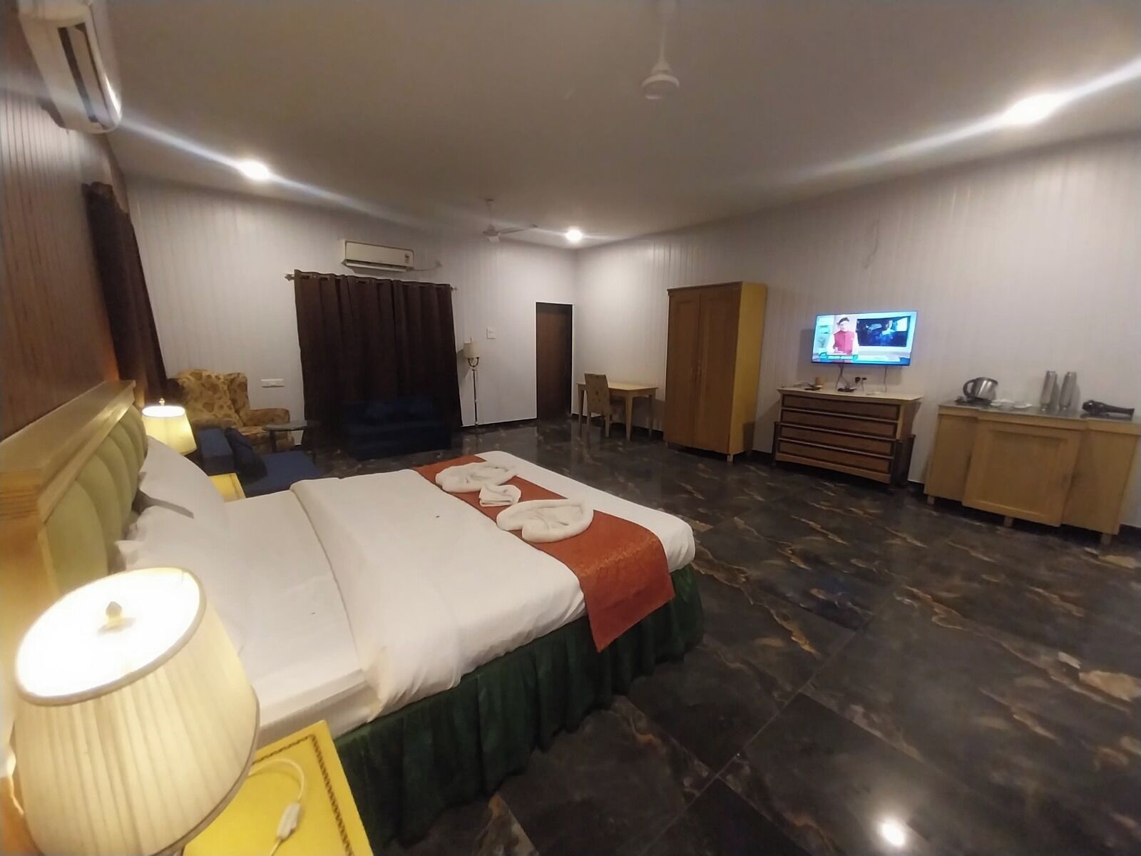 A hotel room with a bed, a desk, a television, and a wardrobe.