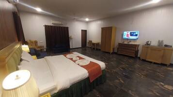A hotel room with a bed, a desk, a television, and a wardrobe.