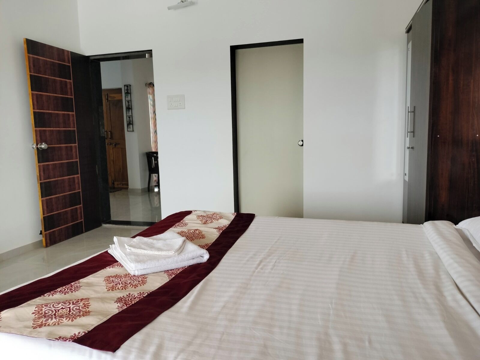 Una habitación de hotel con una cama, un armario de madera y una puerta que da a otra habitación.