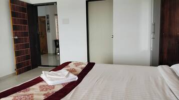 Una habitación de hotel con una cama, un armario de madera y una puerta que da a otra habitación.