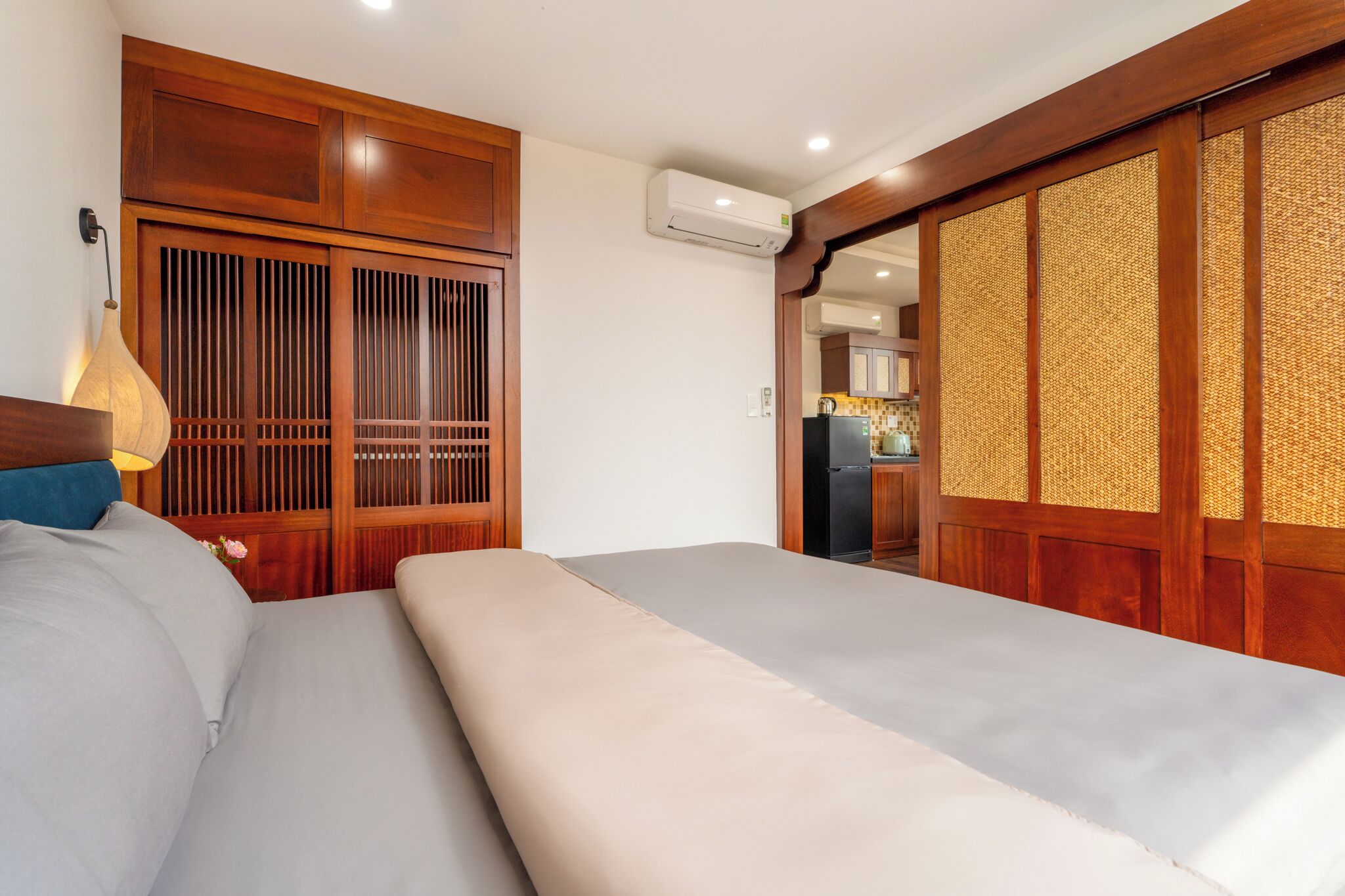Een hotelkamer met een bed, een houten garderobe en een kitchenette.