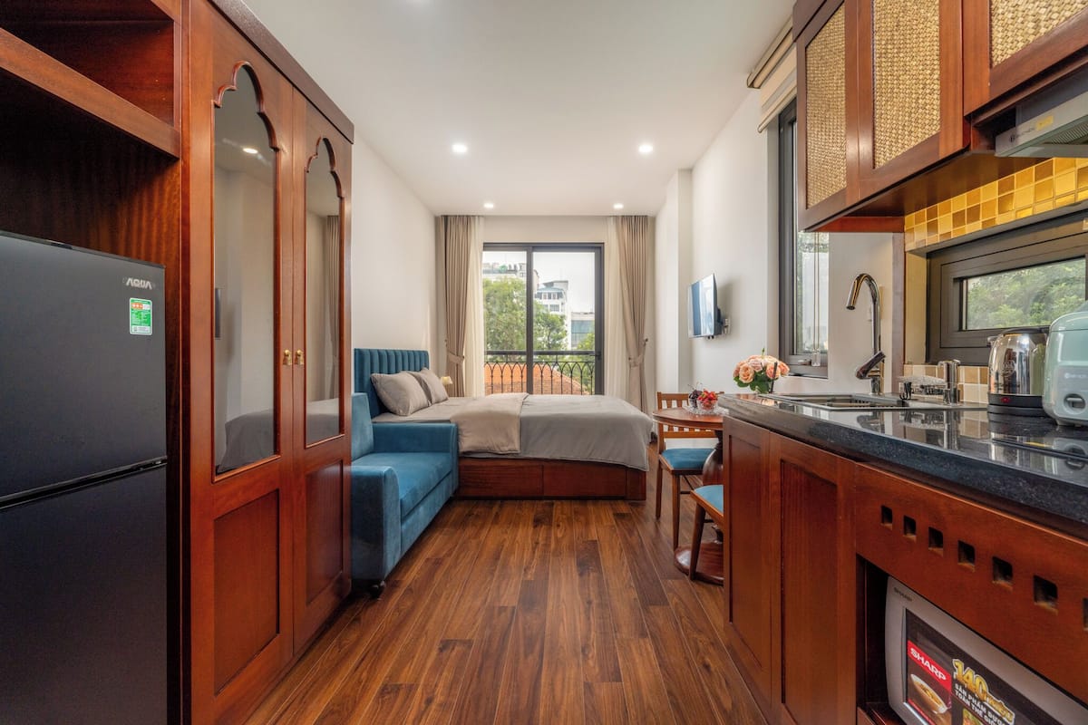 A compact kitchen with wooden cabinets, a refrigerator, and a dining area with a table and chairs.