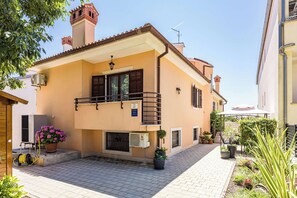 A two-story building with a balcony, a small garden area, and a paved courtyard. - Olea Magica / Studio apartment Rosignola (Rovinj)