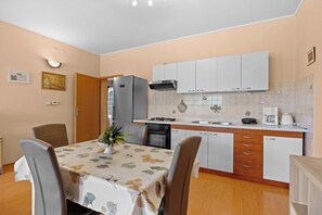 A compact kitchen with white cabinets, a built-in oven, and a coffee maker. - Olea Magica / 2B Apt Buza with garden (Rovinj)
