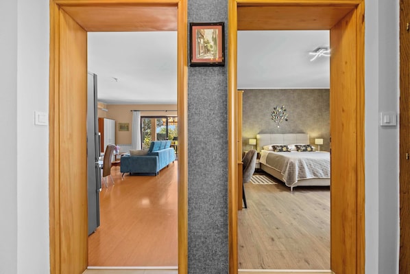 A room with a bed, a chair, and a desk. There is a window with curtains and a picture frame on the wall.