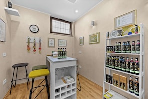 A room with a white bar stool, a shelf with framed certificates, and a wall-mounted clock.